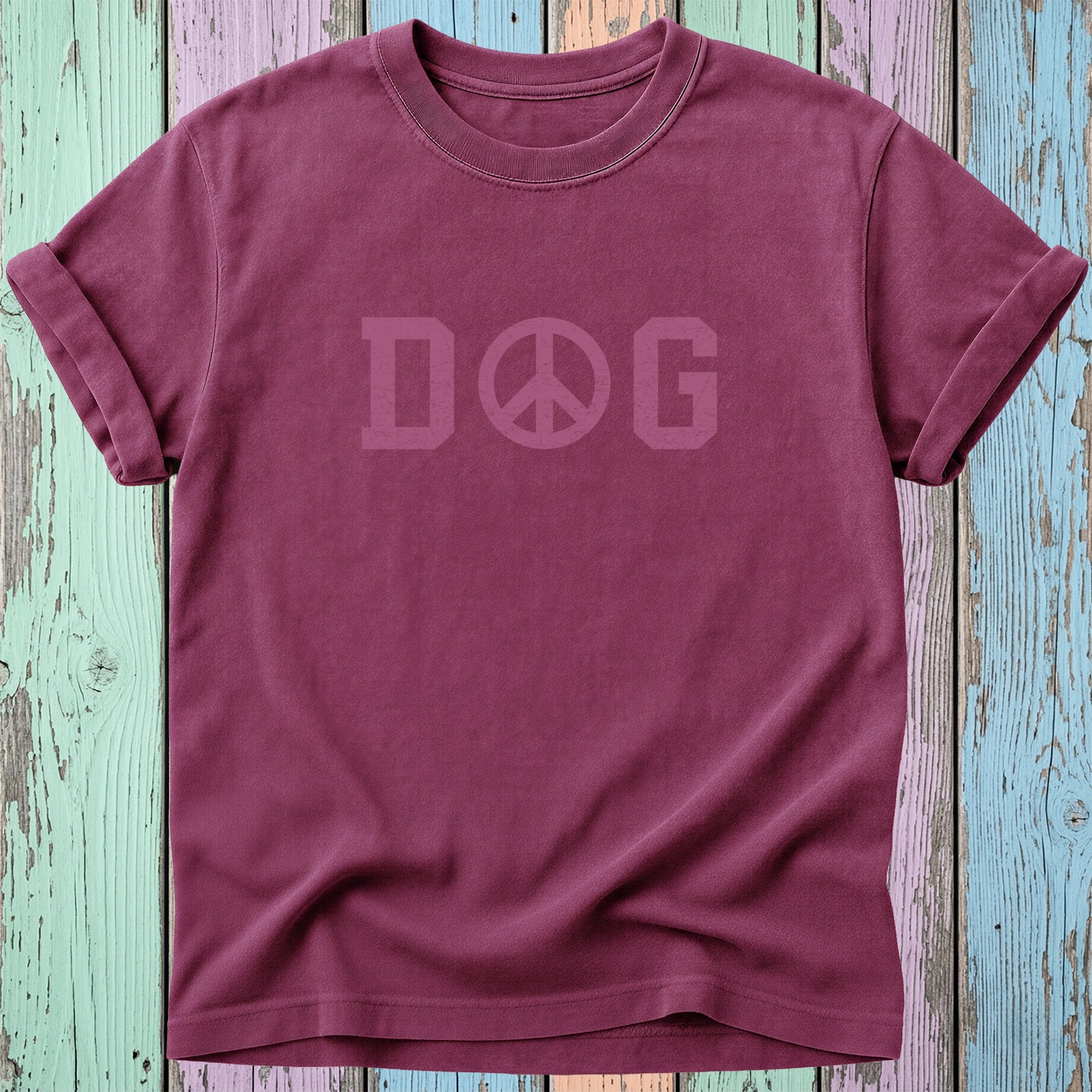 Maroon t-shirt with "DOG PEACE" text in a lighter shade, on a distressed wooden background.
