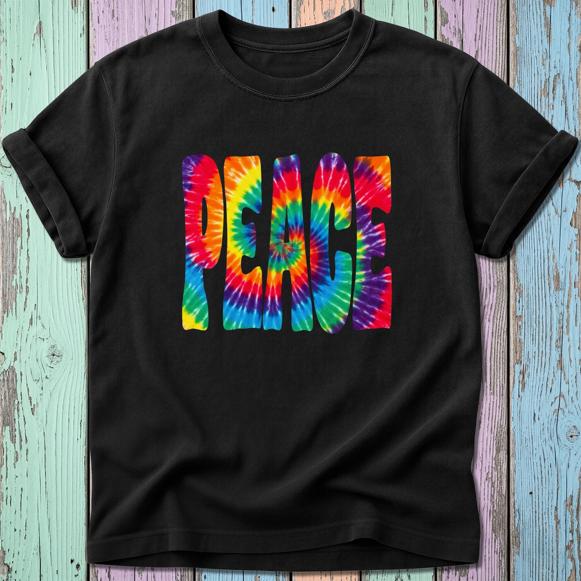 Black t-shirt with tie-dye "PEACE" graphic on a colorful wooden background.