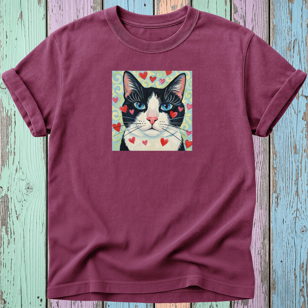 T-shirt featuring a stylized black and white cat with heart accents on a teal background.