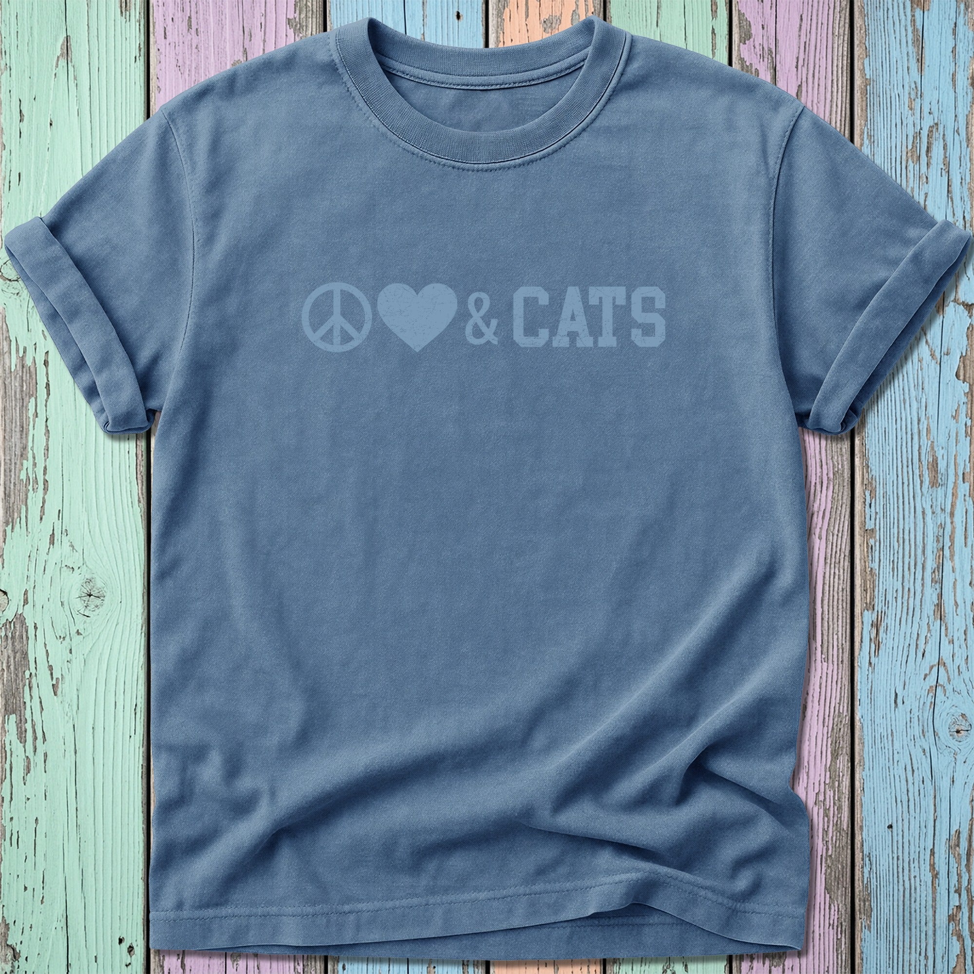Blue t-shirt with graphic "Peace Love Cats" against distressed multicolor wood.