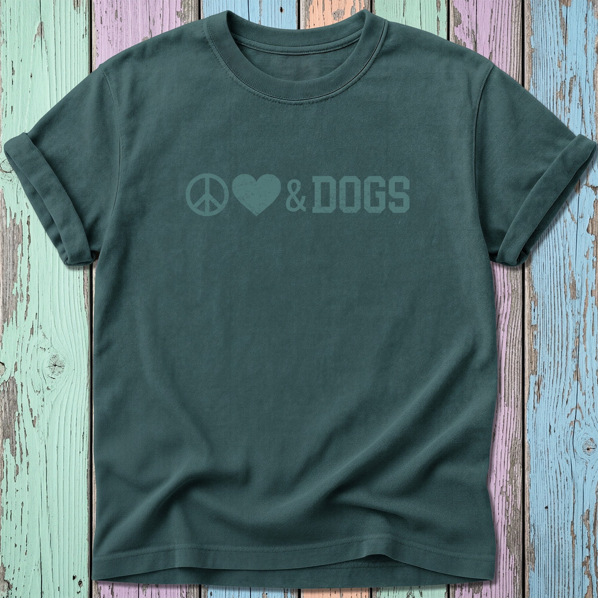 Teal t-shirt with peace, heart, and dogs graphic on a colorful wooden background.